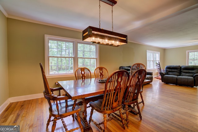 dining area with ornamental molding and light hardwood / wood-style floors