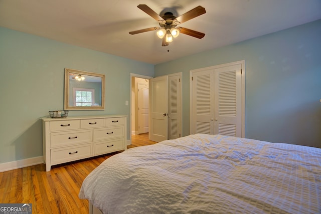 bedroom with two closets, ceiling fan, and light hardwood / wood-style flooring