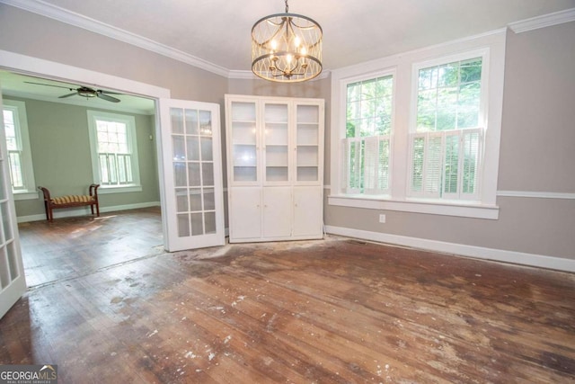 unfurnished dining area with a healthy amount of sunlight, ceiling fan with notable chandelier, and dark wood-type flooring