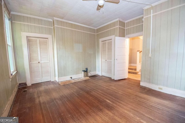 unfurnished bedroom with ceiling fan, hardwood / wood-style flooring, wood walls, and ornamental molding