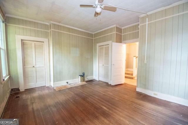 unfurnished bedroom with ornamental molding, wood walls, ceiling fan, and hardwood / wood-style floors