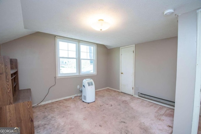 interior space featuring lofted ceiling, light colored carpet, a textured ceiling, and baseboard heating