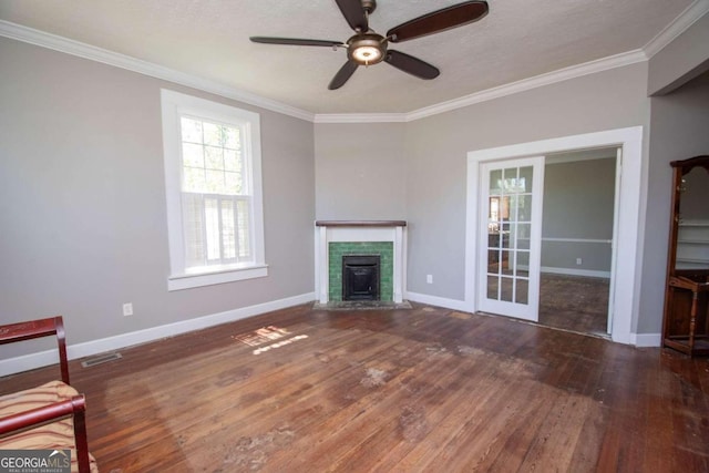 unfurnished living room with crown molding, dark hardwood / wood-style flooring, ceiling fan, and a wood stove