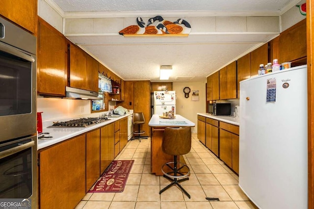 kitchen featuring a textured ceiling, stainless steel appliances, light tile patterned floors, and a center island