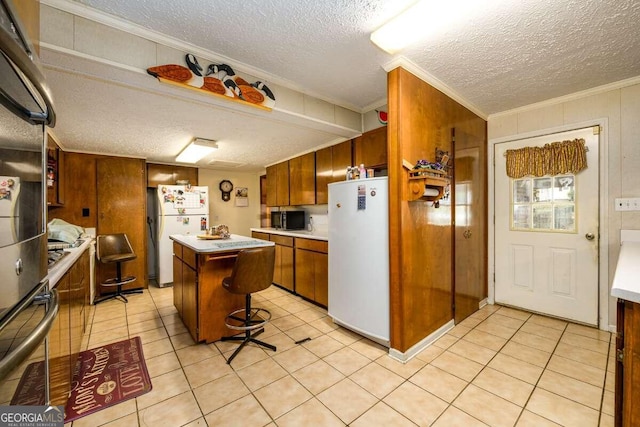 kitchen with light tile patterned flooring, a textured ceiling, appliances with stainless steel finishes, a center island, and crown molding