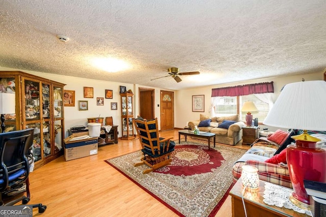 living room featuring a textured ceiling, wood-type flooring, and ceiling fan