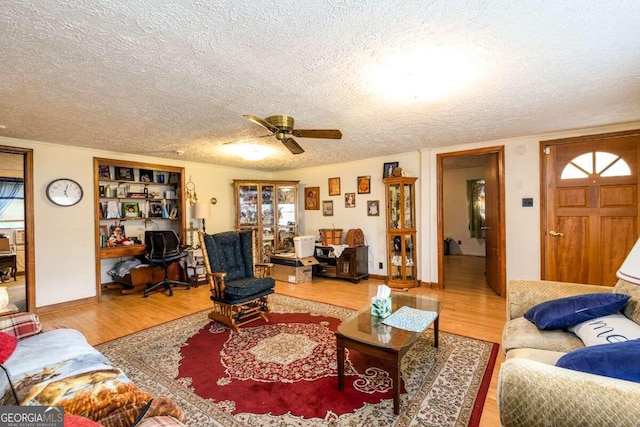 living room with ceiling fan, built in desk, a textured ceiling, and hardwood / wood-style floors