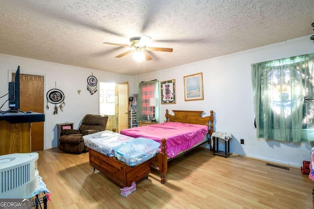 bedroom with ceiling fan, a textured ceiling, light hardwood / wood-style flooring, and ornamental molding