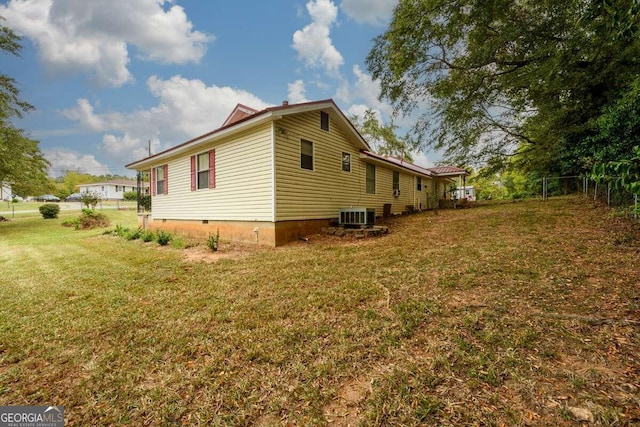 view of side of home featuring central air condition unit and a yard