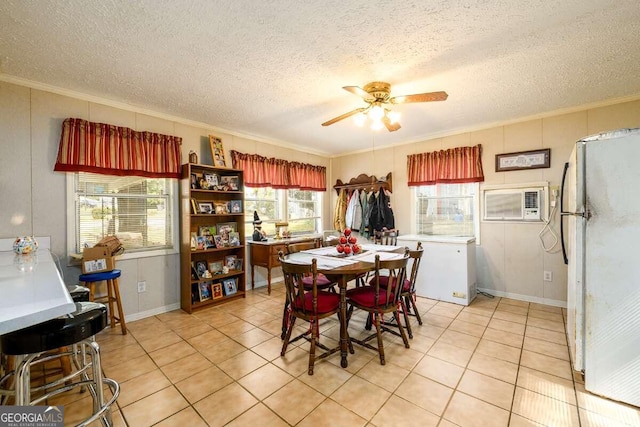 tiled dining area with ornamental molding, a wall unit AC, a textured ceiling, and ceiling fan