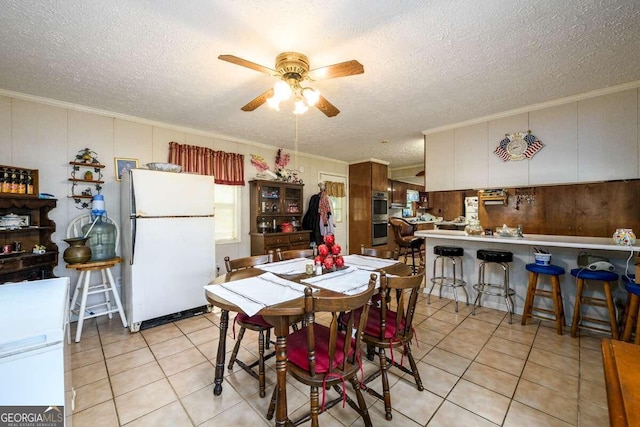 tiled dining area featuring ceiling fan, a textured ceiling, and ornamental molding