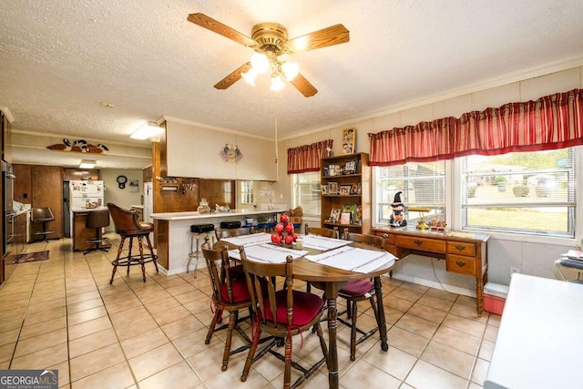 tiled dining space featuring a textured ceiling, ornamental molding, and ceiling fan