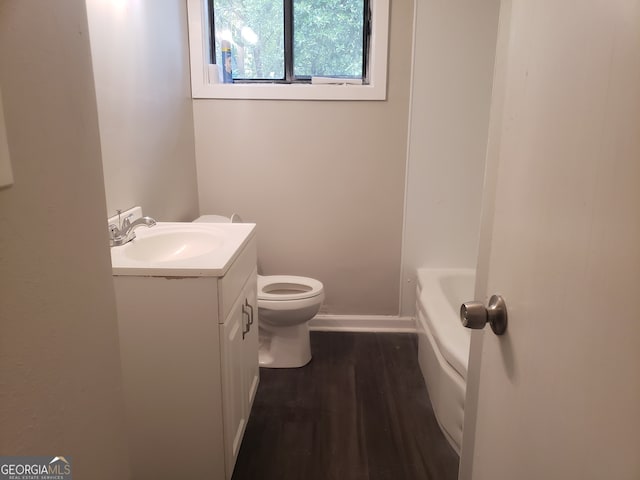 bathroom with wood-type flooring, toilet, vanity, and a washtub