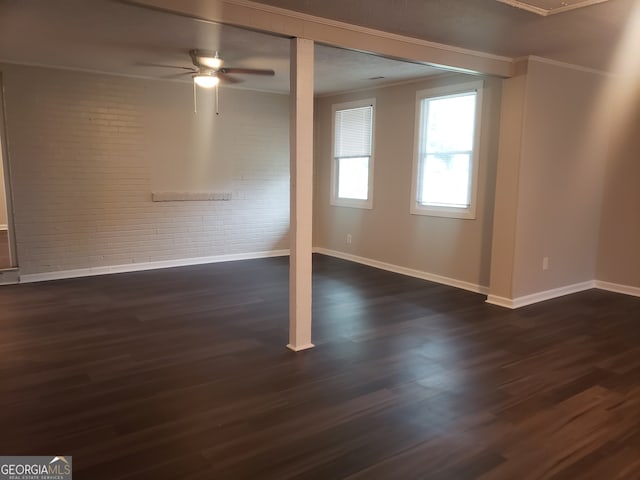 empty room featuring ornamental molding, ceiling fan, brick wall, and dark wood-type flooring