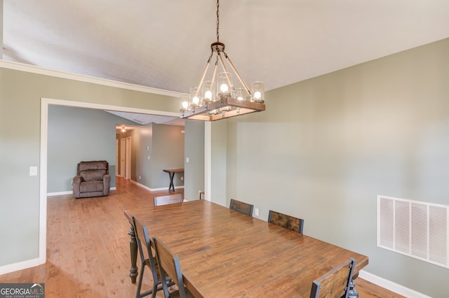 dining area featuring ornamental molding, light hardwood / wood-style flooring, and a notable chandelier