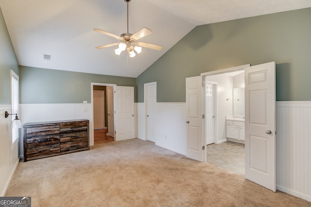 unfurnished bedroom featuring lofted ceiling, light carpet, ceiling fan, and ensuite bath