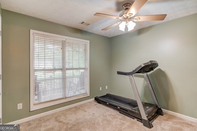 exercise area with light carpet, ceiling fan, and a textured ceiling