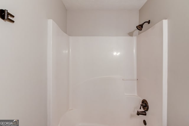 bathroom featuring shower / bathing tub combination and a textured ceiling