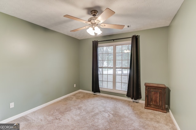 empty room featuring light carpet, a textured ceiling, and ceiling fan