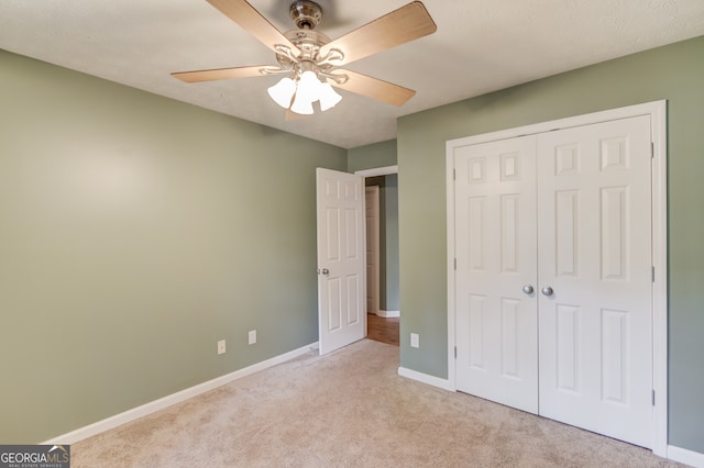 unfurnished bedroom featuring ceiling fan, a closet, and light carpet