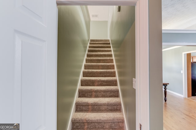 stairs with crown molding and hardwood / wood-style floors