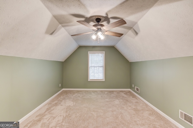 bonus room with a textured ceiling, vaulted ceiling, ceiling fan, and light colored carpet