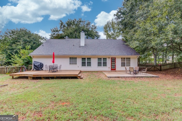 back of property with a lawn, a wooden deck, and a patio area