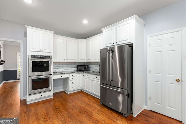 kitchen with white cabinets, backsplash, appliances with stainless steel finishes, and dark hardwood / wood-style floors