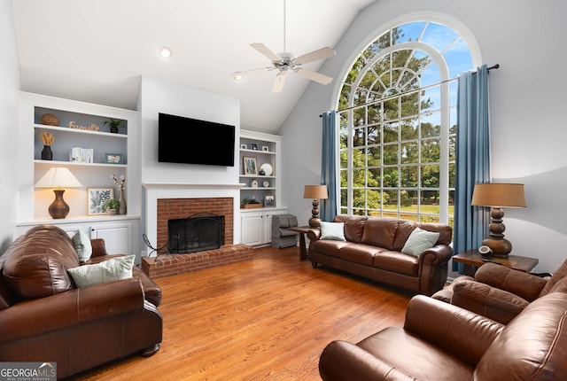 living room featuring a brick fireplace, vaulted ceiling, light hardwood / wood-style floors, and ceiling fan