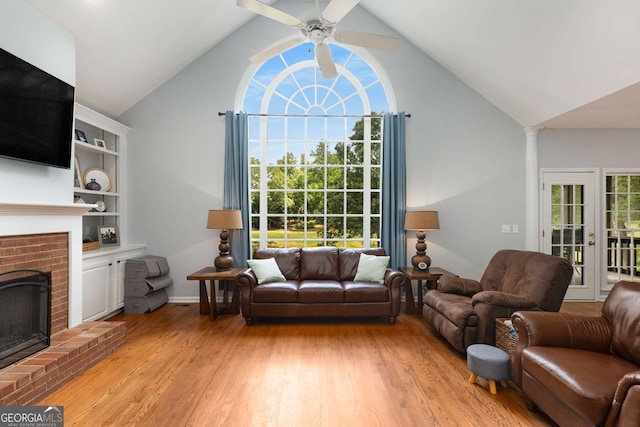 living room with ceiling fan, vaulted ceiling, a fireplace, and light hardwood / wood-style floors