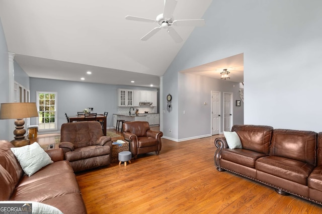 living room with high vaulted ceiling, sink, light hardwood / wood-style flooring, and ceiling fan