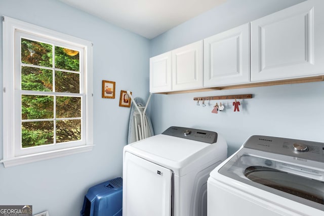 clothes washing area with cabinets and washer and clothes dryer