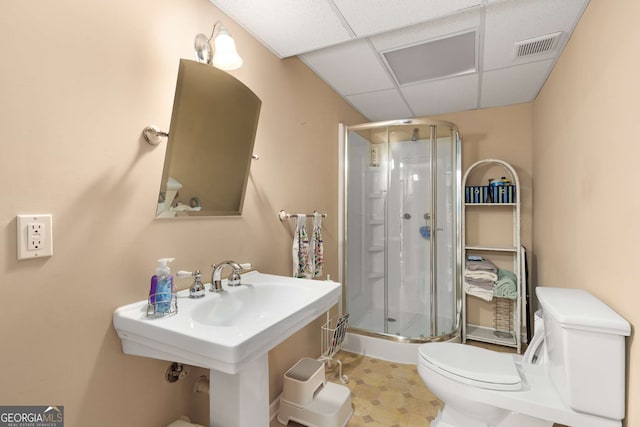 bathroom with a paneled ceiling, toilet, and a shower with shower door