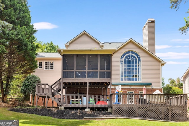 rear view of house featuring a deck, a yard, and a sunroom