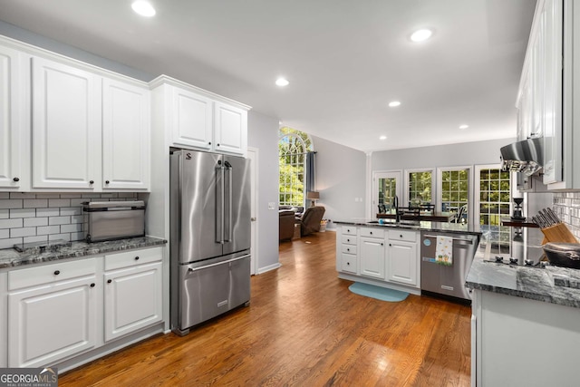 kitchen with white cabinets, sink, dark wood-type flooring, appliances with stainless steel finishes, and dark stone counters