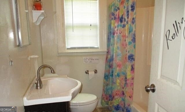 full bathroom with shower / tub combo with curtain, vanity, and toilet