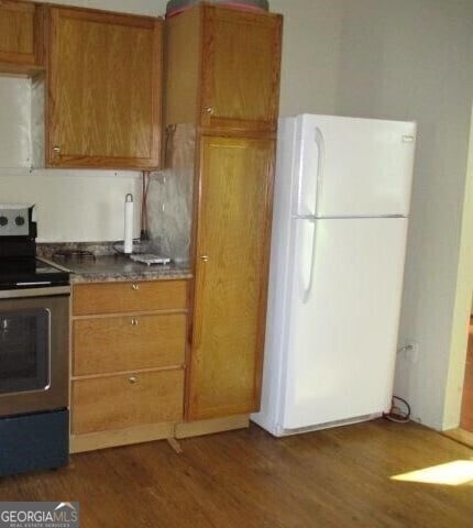 kitchen with dark wood-type flooring, electric range, and white fridge