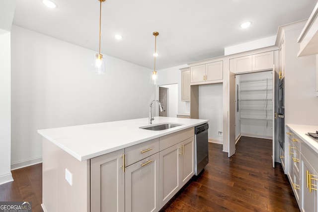 kitchen featuring dark hardwood / wood-style flooring, decorative light fixtures, stainless steel dishwasher, a kitchen island with sink, and sink