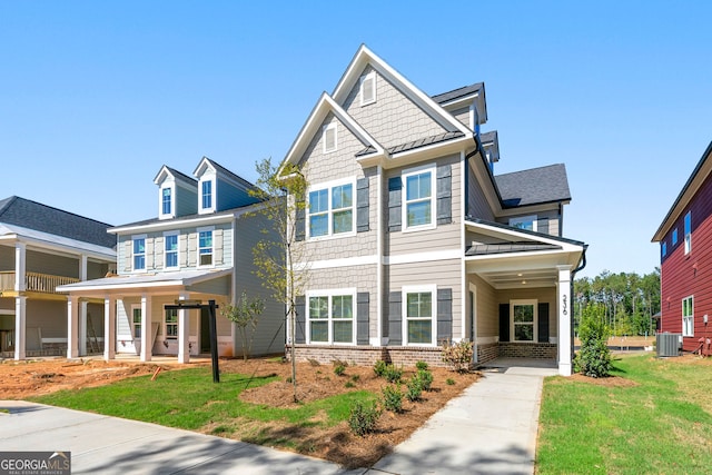 craftsman inspired home with a balcony, a front lawn, and central AC unit