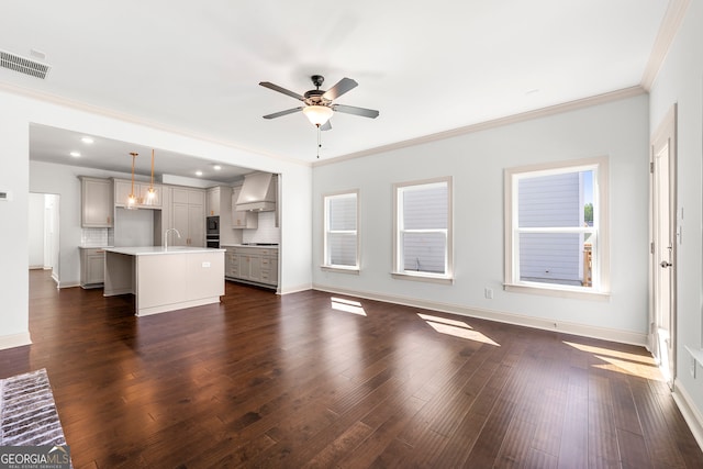 unfurnished living room with crown molding, plenty of natural light, and dark hardwood / wood-style flooring