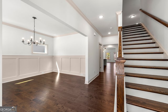 entrance foyer with an inviting chandelier, crown molding, and dark hardwood / wood-style floors