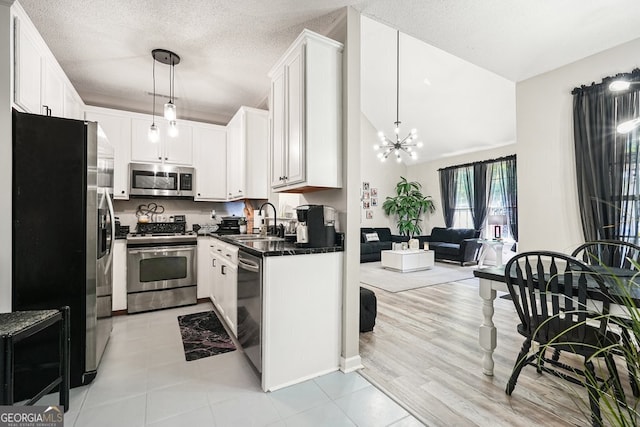 kitchen featuring sink, decorative light fixtures, white cabinetry, appliances with stainless steel finishes, and a textured ceiling