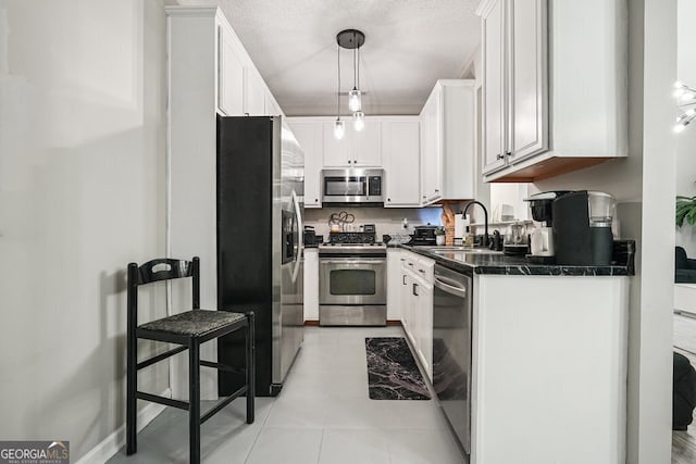 kitchen with appliances with stainless steel finishes, sink, decorative light fixtures, and white cabinets