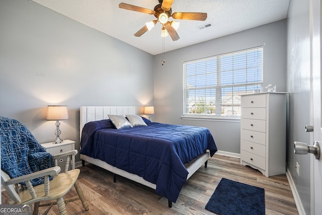 bedroom with a textured ceiling, hardwood / wood-style flooring, and ceiling fan