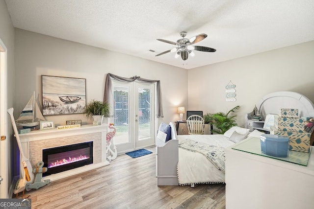 bedroom with a textured ceiling, light wood-type flooring, access to outside, and ceiling fan