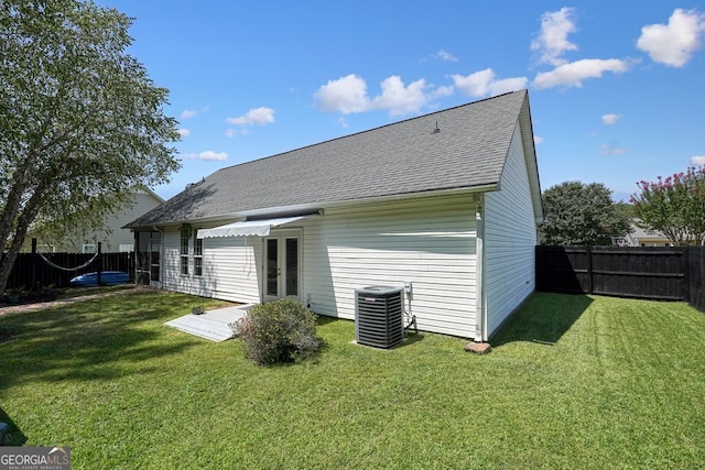 back of property with central air condition unit and a yard