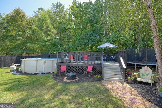 view of yard featuring a pool side deck and a trampoline