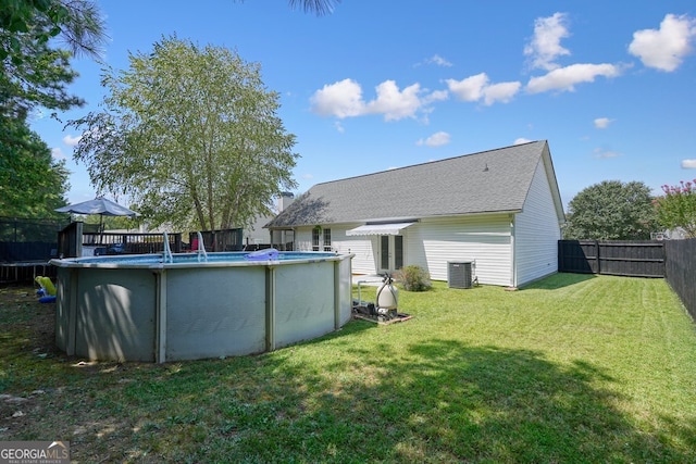 back of house featuring a fenced in pool, cooling unit, and a lawn