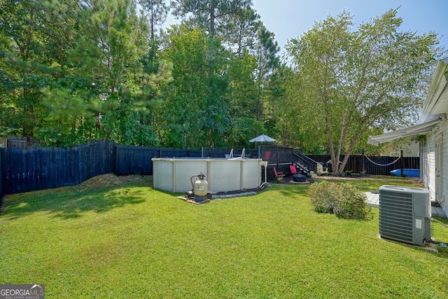 view of yard with central AC unit and a fenced in pool