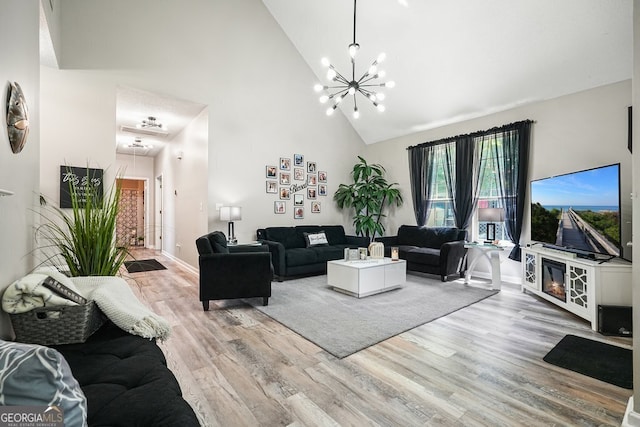 living room with light hardwood / wood-style floors, an inviting chandelier, and high vaulted ceiling